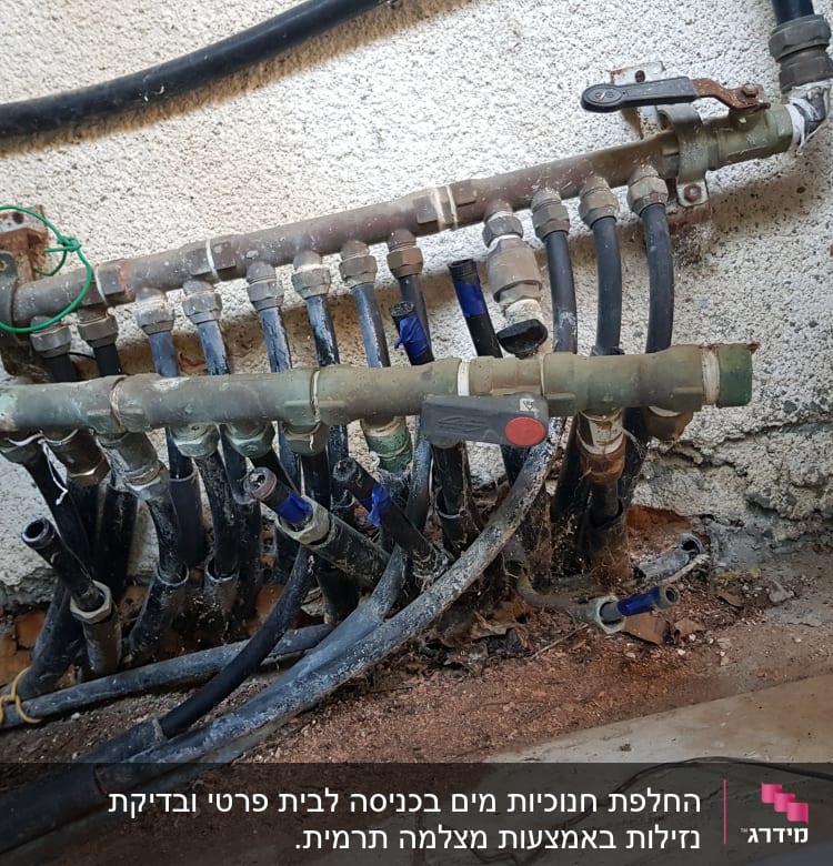 צינורות מים מחוברים לברזים על קיר בטון